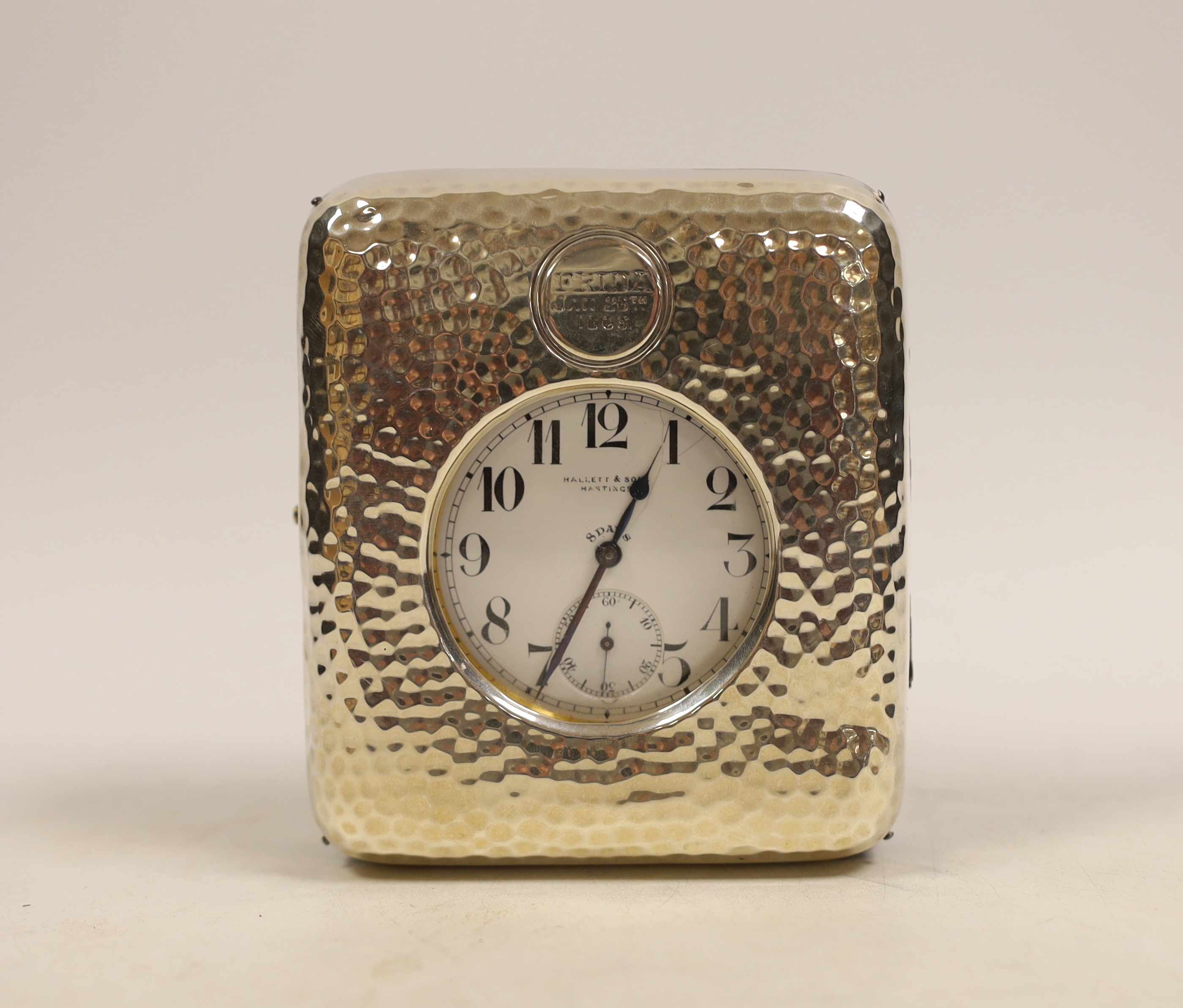 A vintage 'Goliath' pocket watch housed in an Edwardian hammered silver bedside watch stand by William Comyns, London, 1902, 11cm.